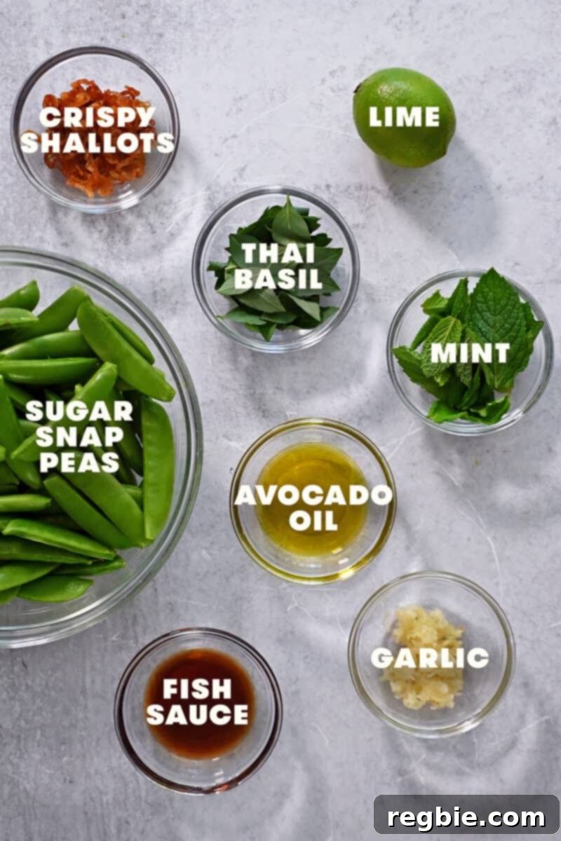 Speedy Southeast Asian Snap Pea Sensation 4 An overhead shot of the raw ingredients for this quick sugar snap pea recipe, including fresh garlic, a bottle of fish sauce, lime juice, various fresh herbs, and a bowl of crispy shallots.