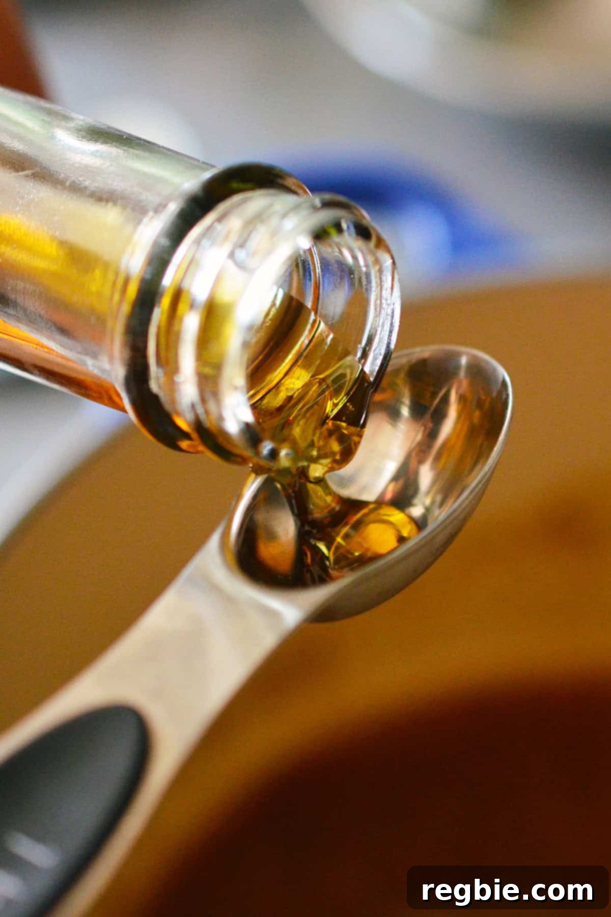 Pouring a stream of toasted sesame oil into a measuring spoon, ready to be added to the finished dressing for a final flavor boost.