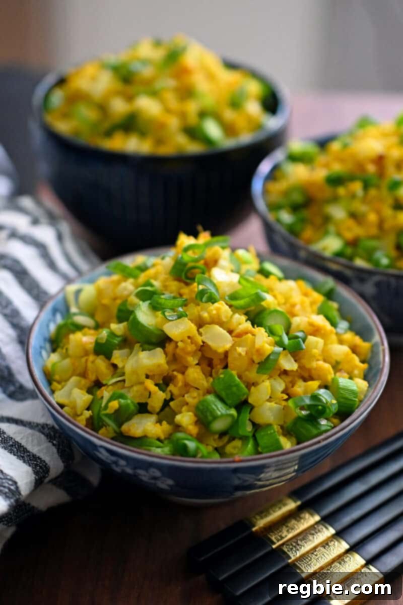 Three bowls of golden cauliflower fried rice, a paleo, whole30, and keto vegetable side dish, glistening with a golden hue.