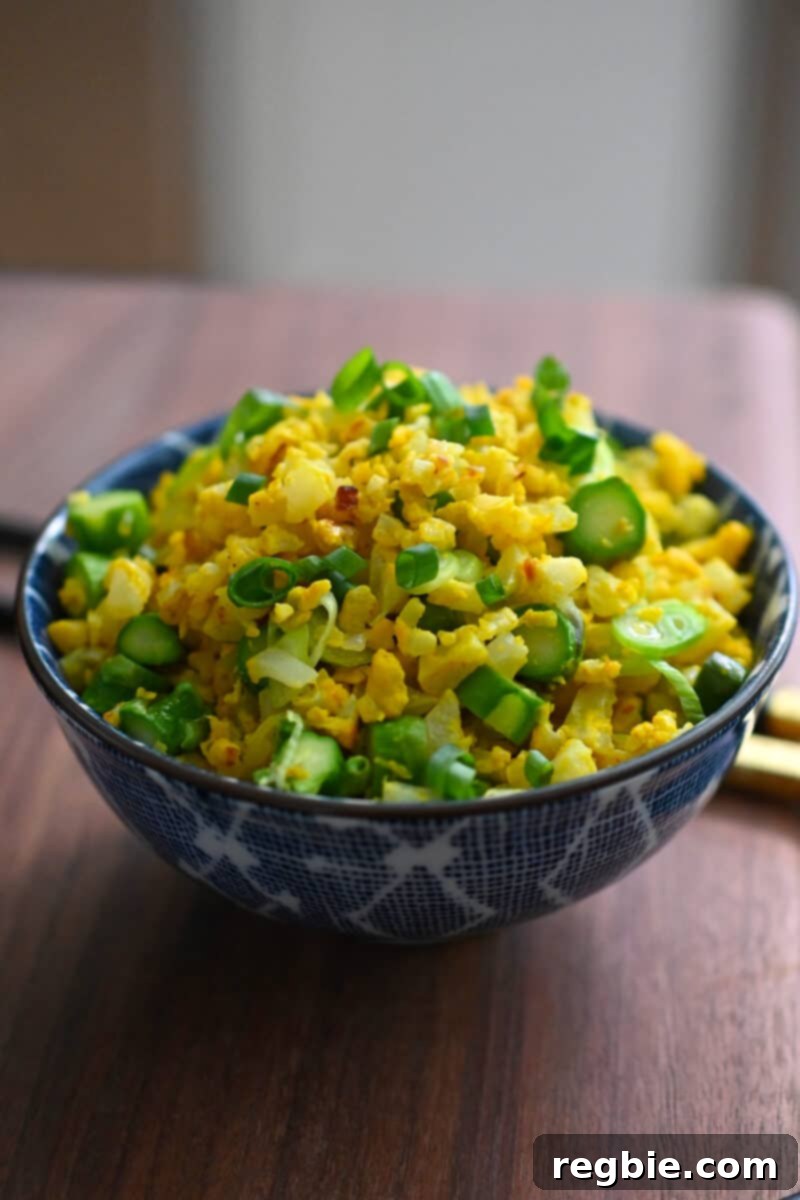 A beautifully presented bowl filled with golden cauliflower fried rice, garnished and ready to be enjoyed.
