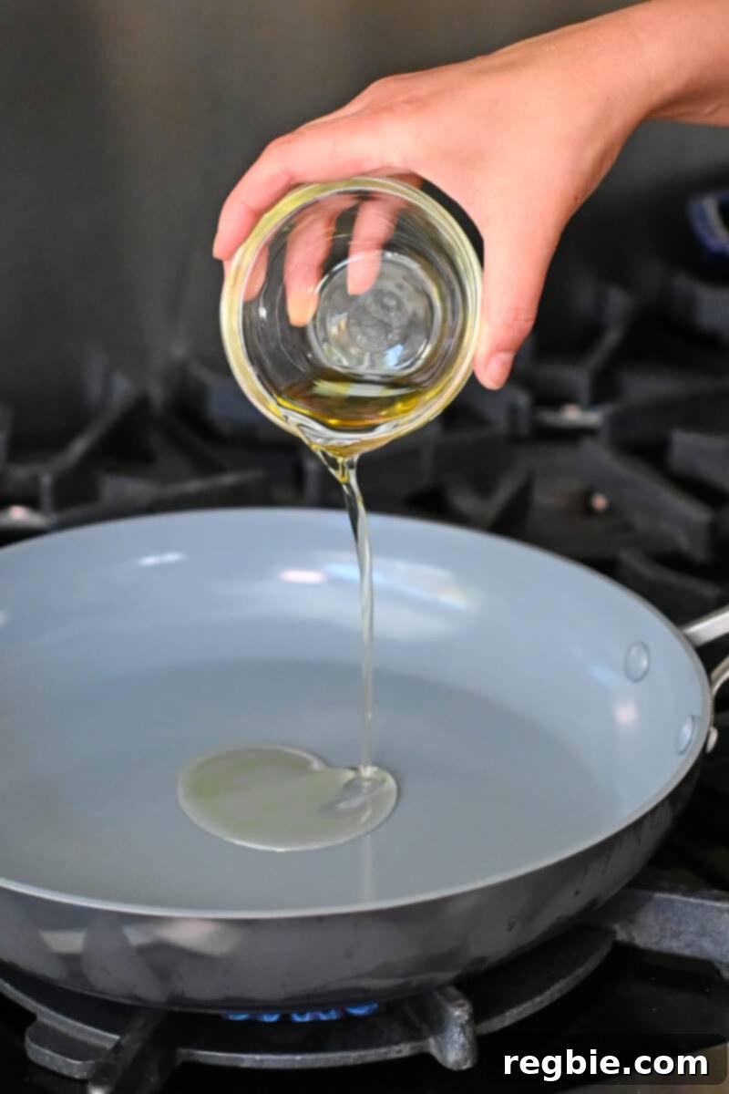 Adding avocado oil to a large skillet, heated to the perfect temperature for stir-frying.