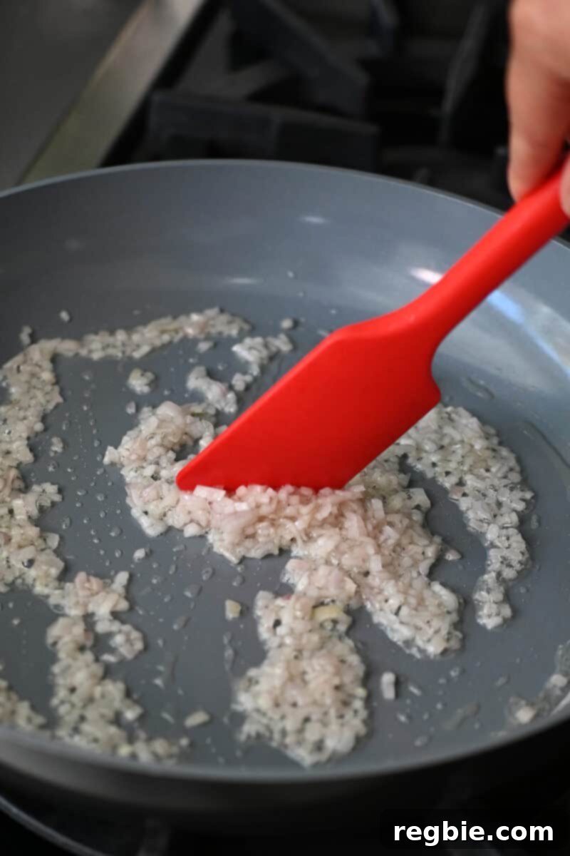 Sauting finely chopped shallots in a skillet with salt and avocado oil, turning translucent and fragrant.