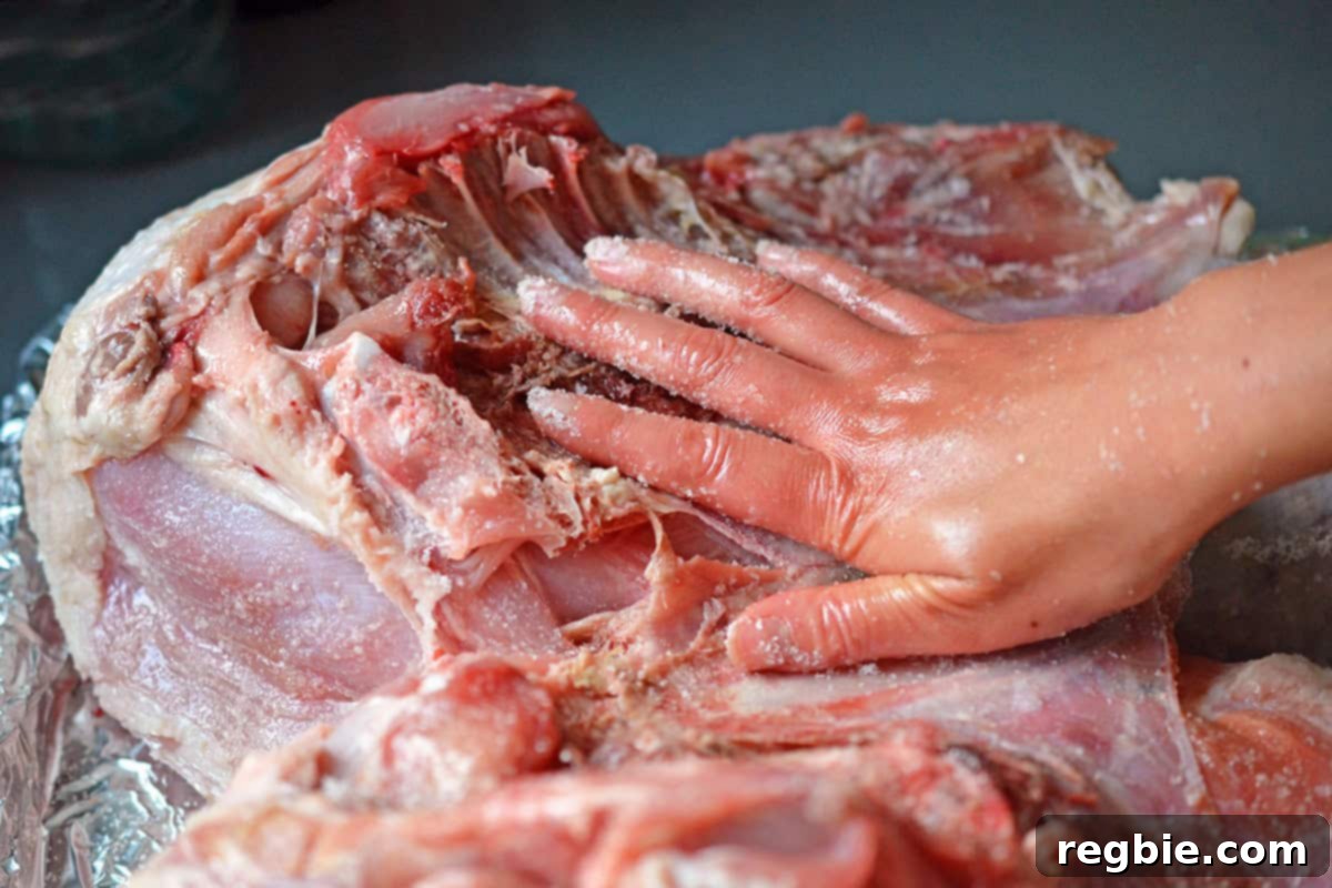 Adding salt to the interior cavity of a spatchcock turkey, ensuring all parts are seasoned.