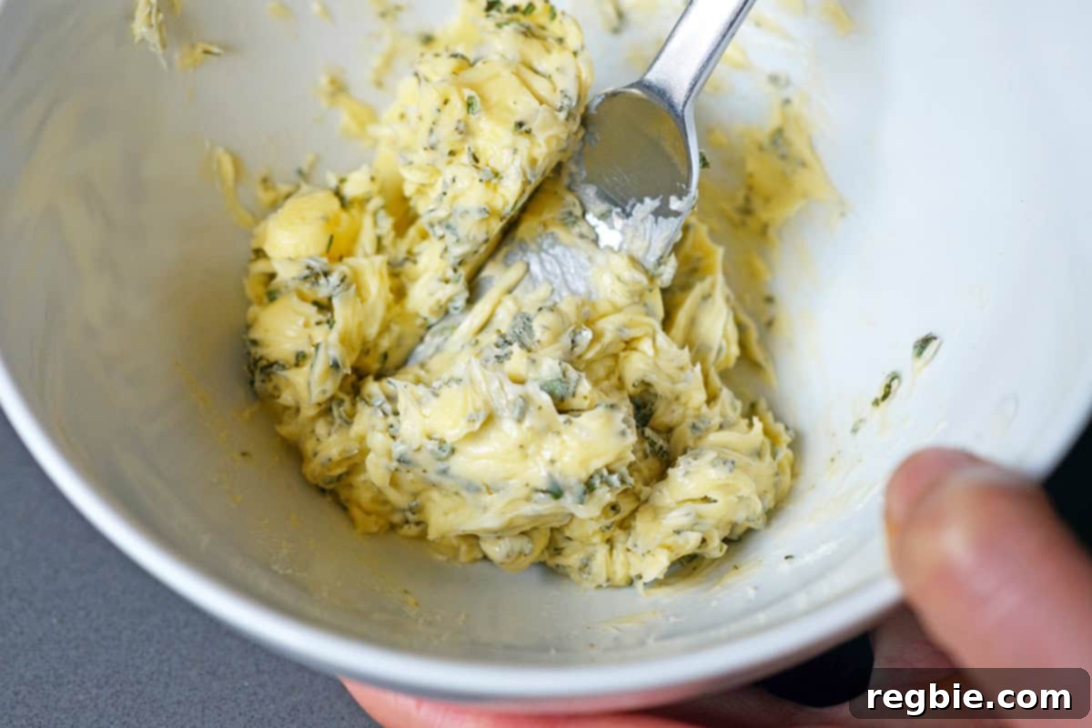 A bowl filled with softened butter thoroughly mixed with minced fresh green herbs, creating compound butter.