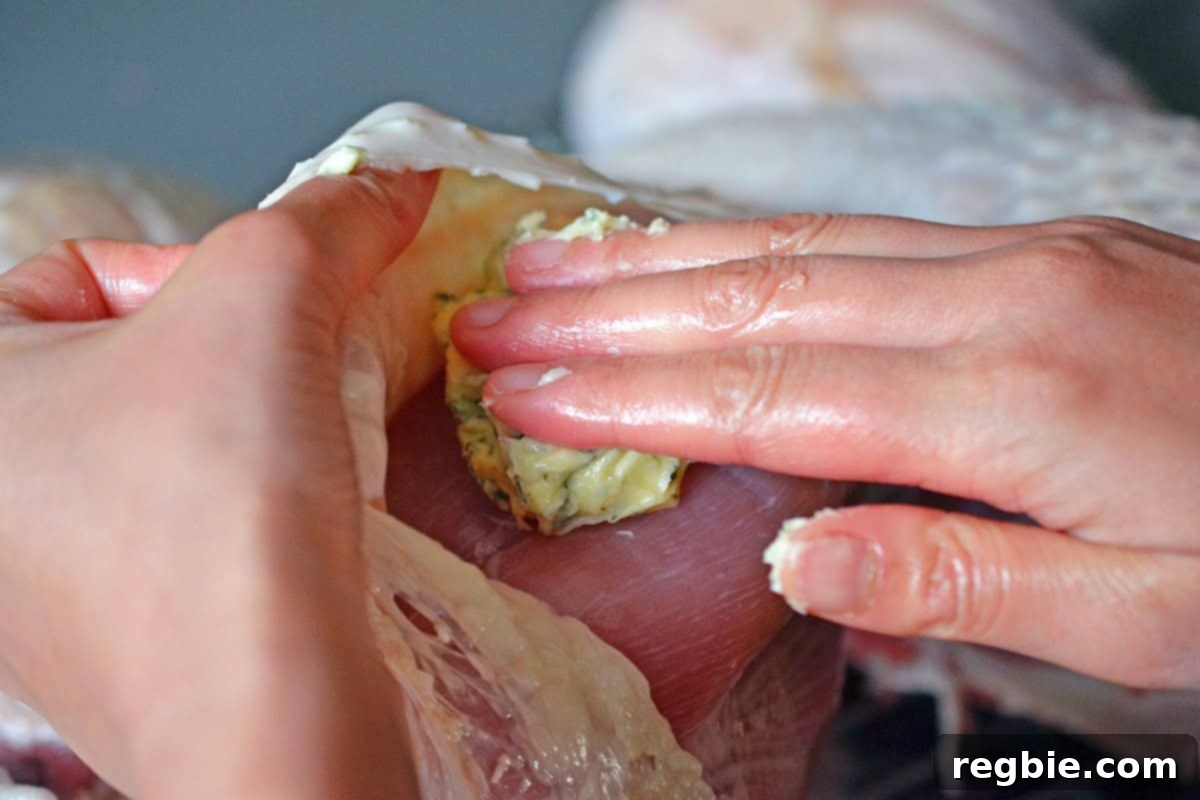 Adding a generous dollop of herb butter onto the breast meat, under the skin, of a spatchcock turkey.