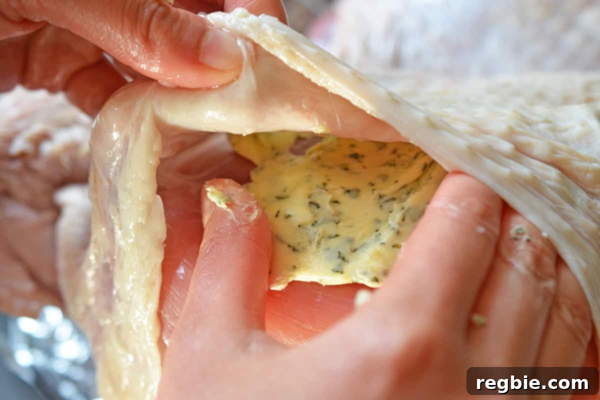 A thick layer of herb butter spread evenly under the skin and over the breast of a raw spatchcock turkey.