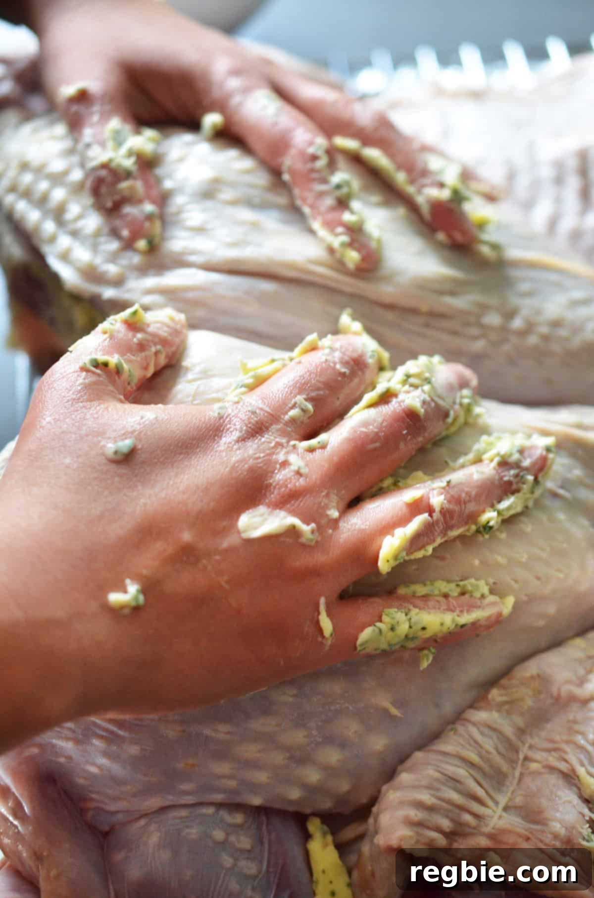 Spreading the remaining herb butter generously over the top skin of a spatchcock turkey before roasting.