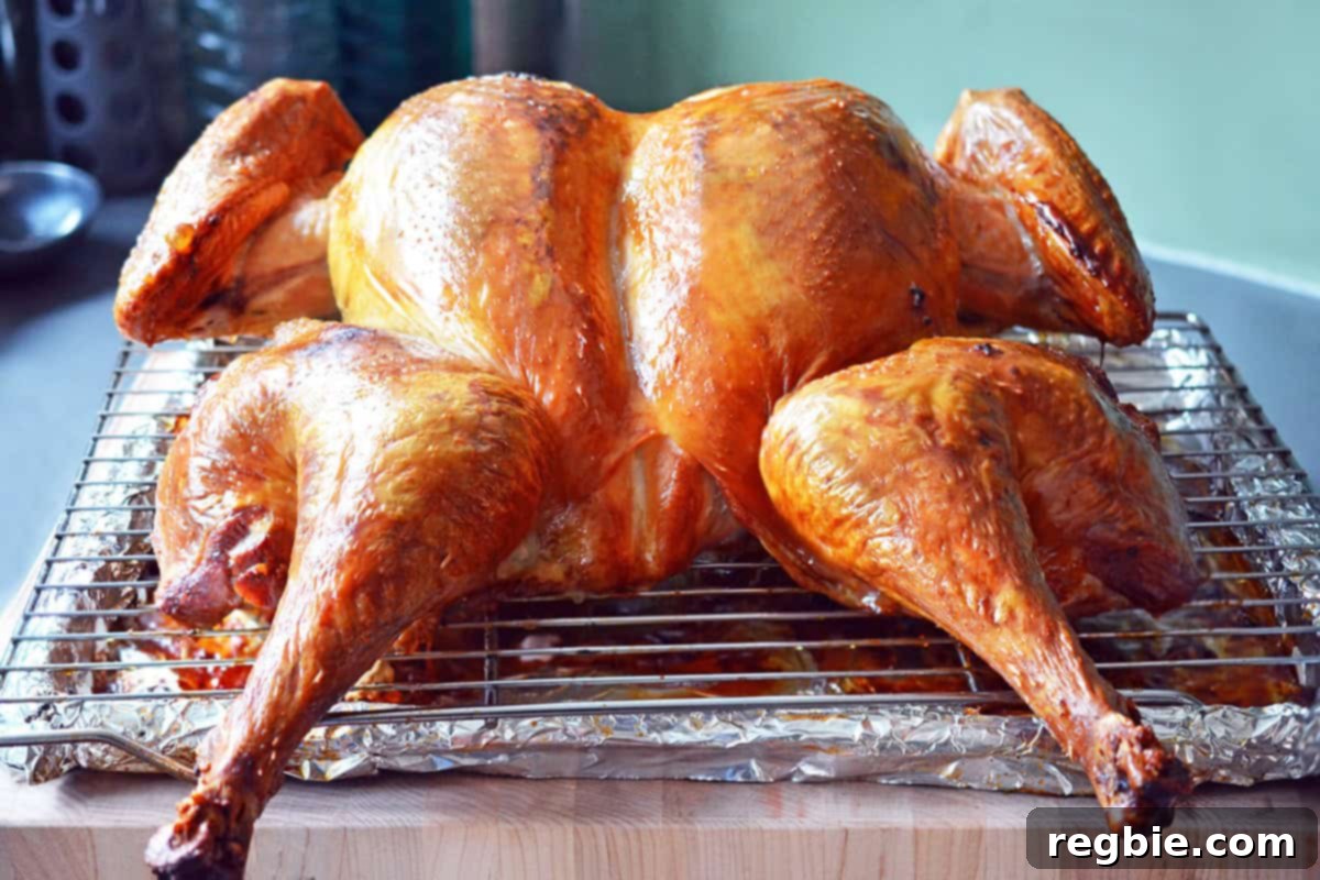 A perfectly roasted golden brown spatchcock turkey resting on a wooden cutting board, cooling before carving.