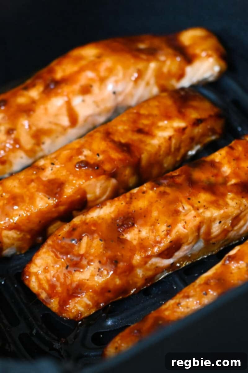 Perfectly air-fried salmon fillets with honey sriracha glaze sitting in an open air fryer, ready to be served.