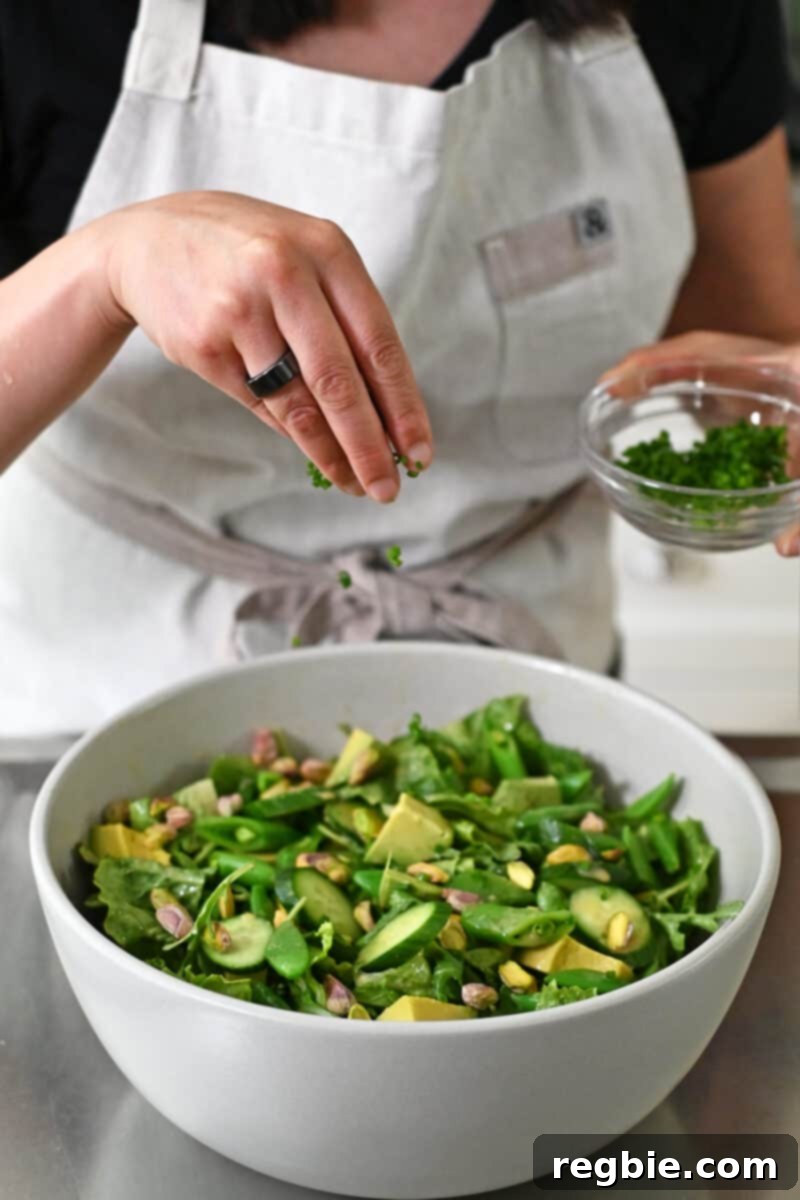 Whole30 Vegan Asian Chopped Salad 13 A hand delicately sprinkling finely sliced fresh chives over a large bowl filled with a beautifully dressed chopped salad, adding the final touch.