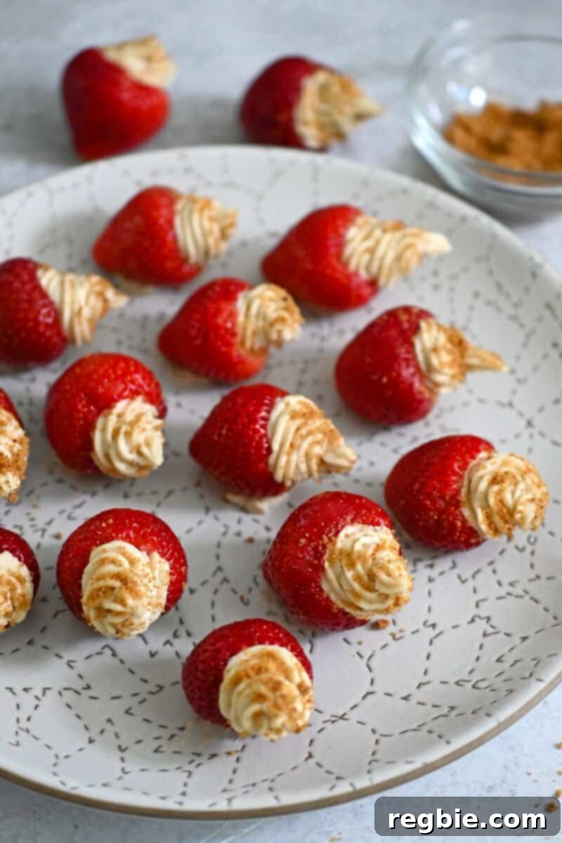 A pristine white plate elegantly topped with several perfectly crafted paleo and vegan cheesecake stuffed strawberries, ready to be enjoyed.