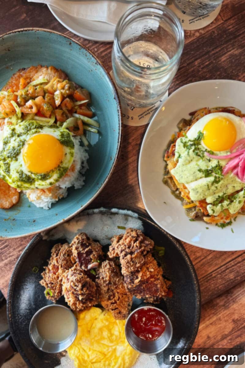 An inviting overhead shot displaying three beautifully arranged breakfast plates at Kiawe Roots in Kauai, showcasing hearty and vibrantly colored dishes.