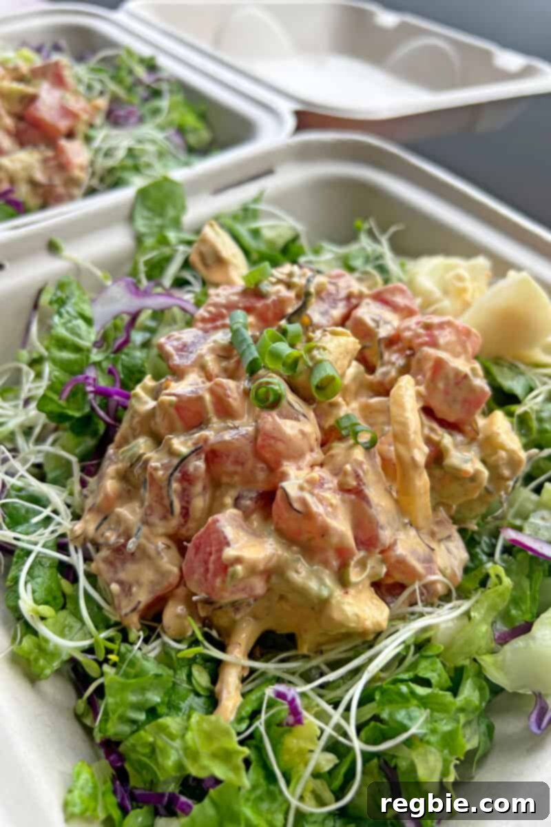 An exquisite overhead view of a gluten-free poke bowl, featuring fresh raw seafood served over crisp salad greens, from Hanalei Poke in Kauai.
