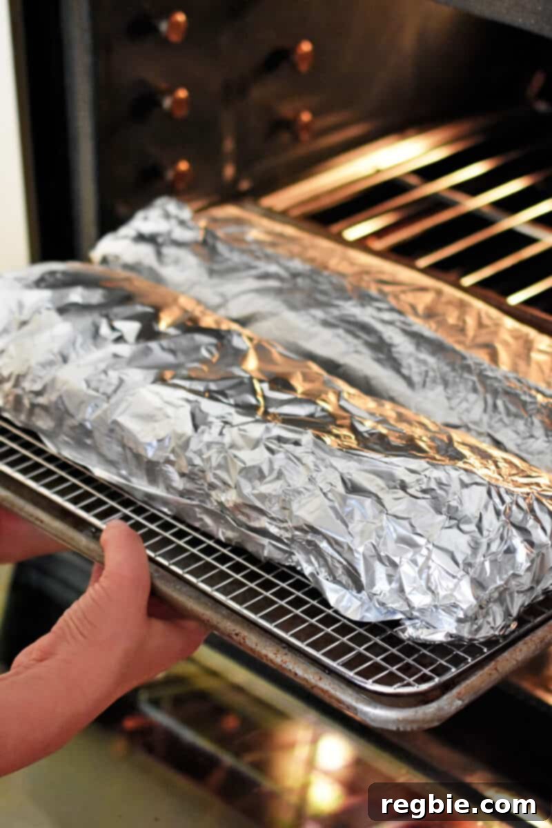 The foil wrapped baby back ribs are placed in an oven.