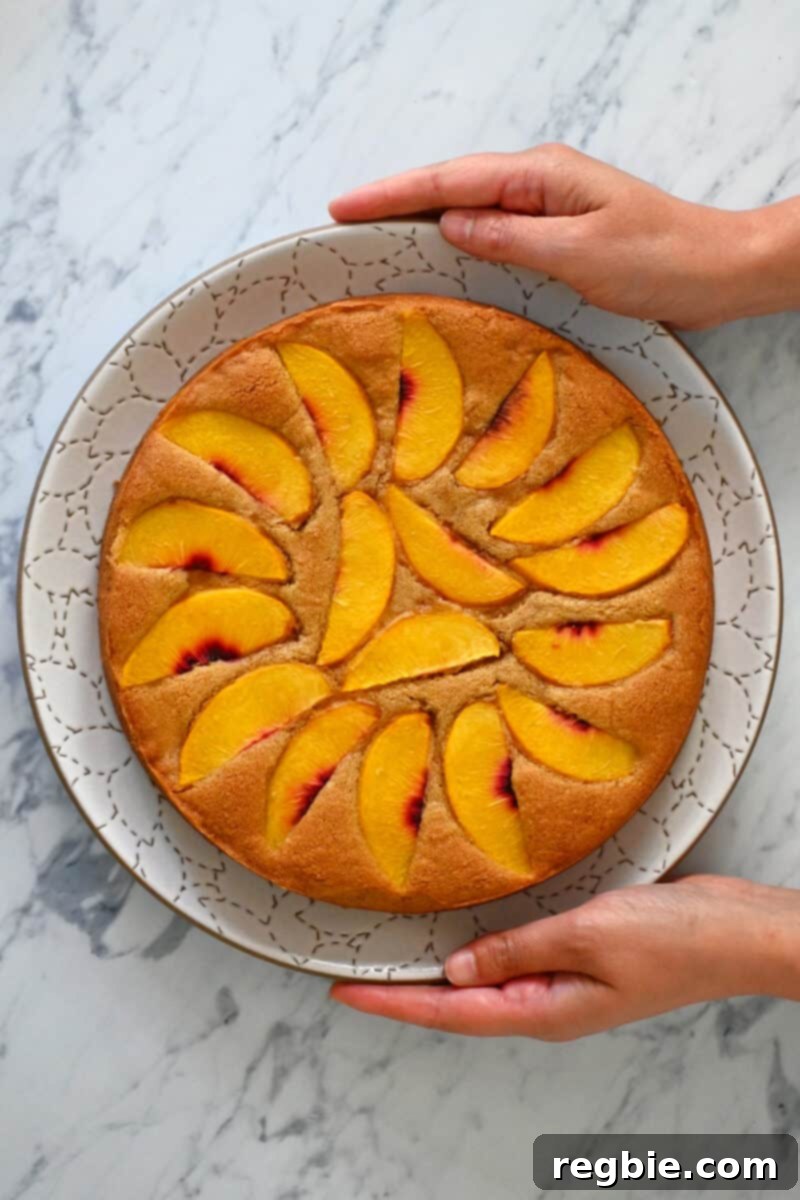 Peach Cloud Cake Paleo Gluten Free 2 An overhead shot of a paleo peach cake on a white plate being held by two hands.