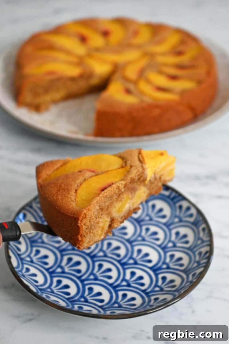 Peach Cloud Cake Paleo Gluten Free 3 A slice of gluten free and paleo peach cake is being placed on a blue and wihite dish.