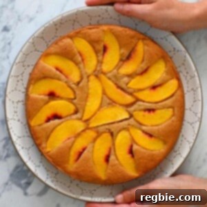 Peach Cloud Cake Paleo Gluten Free 21 An overhead shot of a paleo peach cake on a white plate being held by two hands.