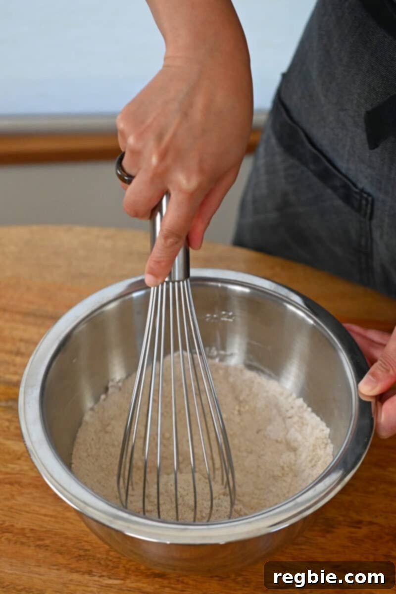 Peach Cloud Cake Paleo Gluten Free 6 Whisking the dry ingredients for paleo peach cake in a large metal bowl.