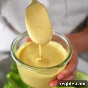 A spoon dipping into a jar of dairy-free Caesar Dressing.