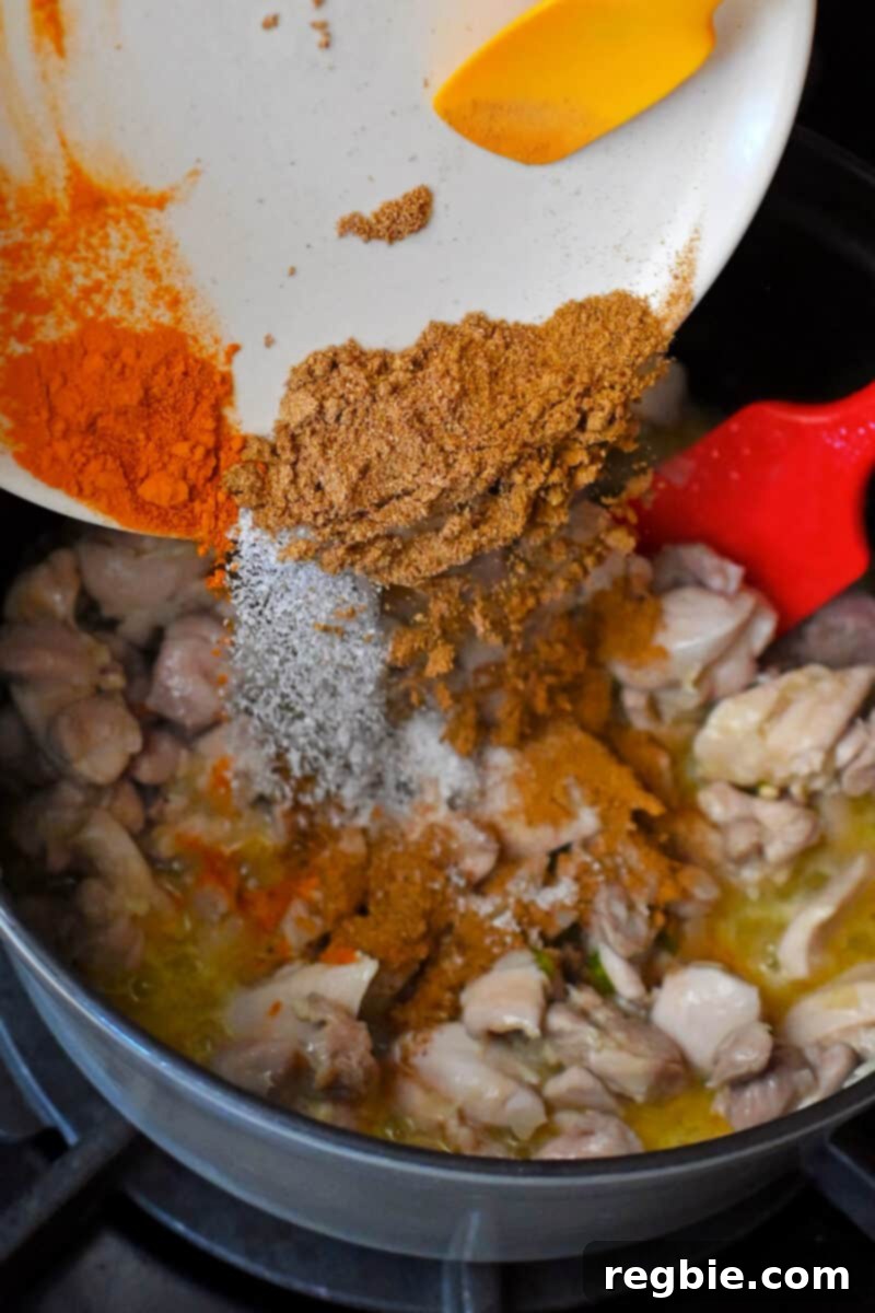 Healthy Instant Pot Chicken Saag Whole30 Keto 12 Adding the dried spices and seasoning to the chicken and onions in a pot to make chicken saag.