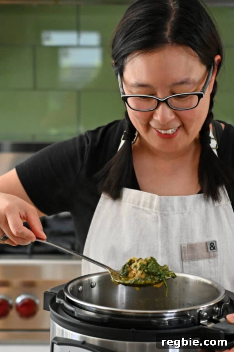 Healthy Instant Pot Chicken Saag Whole30 Keto 3 An Asian woman is scooping up some chicken and spinach curry from an Instant Pot.