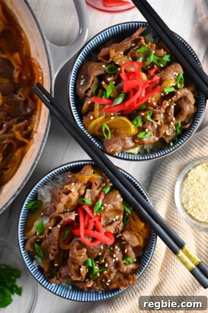 An overhead shot of two bowls of healthy gyudon, Japanese beef and cauliflower rice bowls, garnished with scallions and pickled ginger.