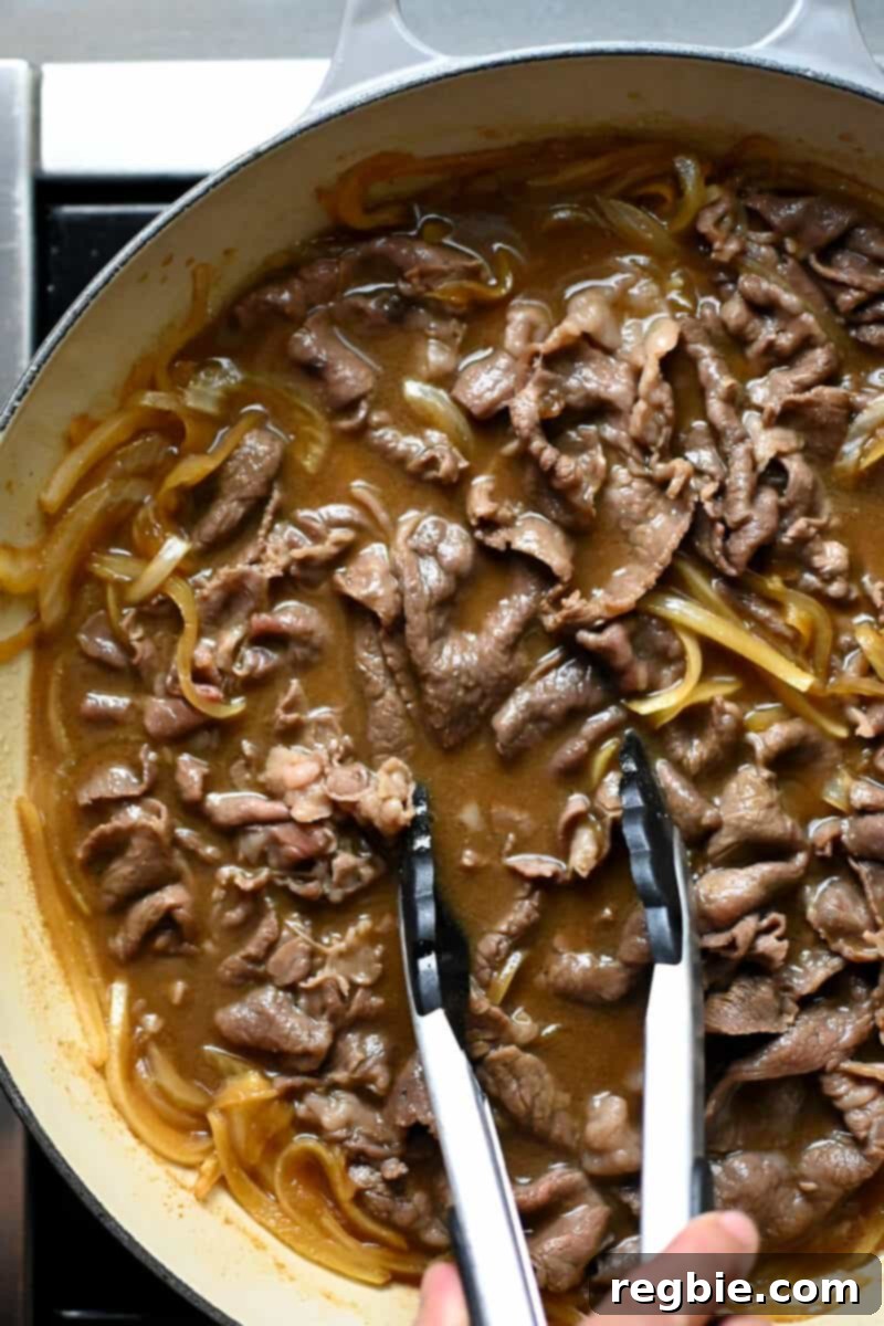 An overhead shot of a skillet filled with fully cooked healthy gyudon, where the beef is brown and no longer pink.