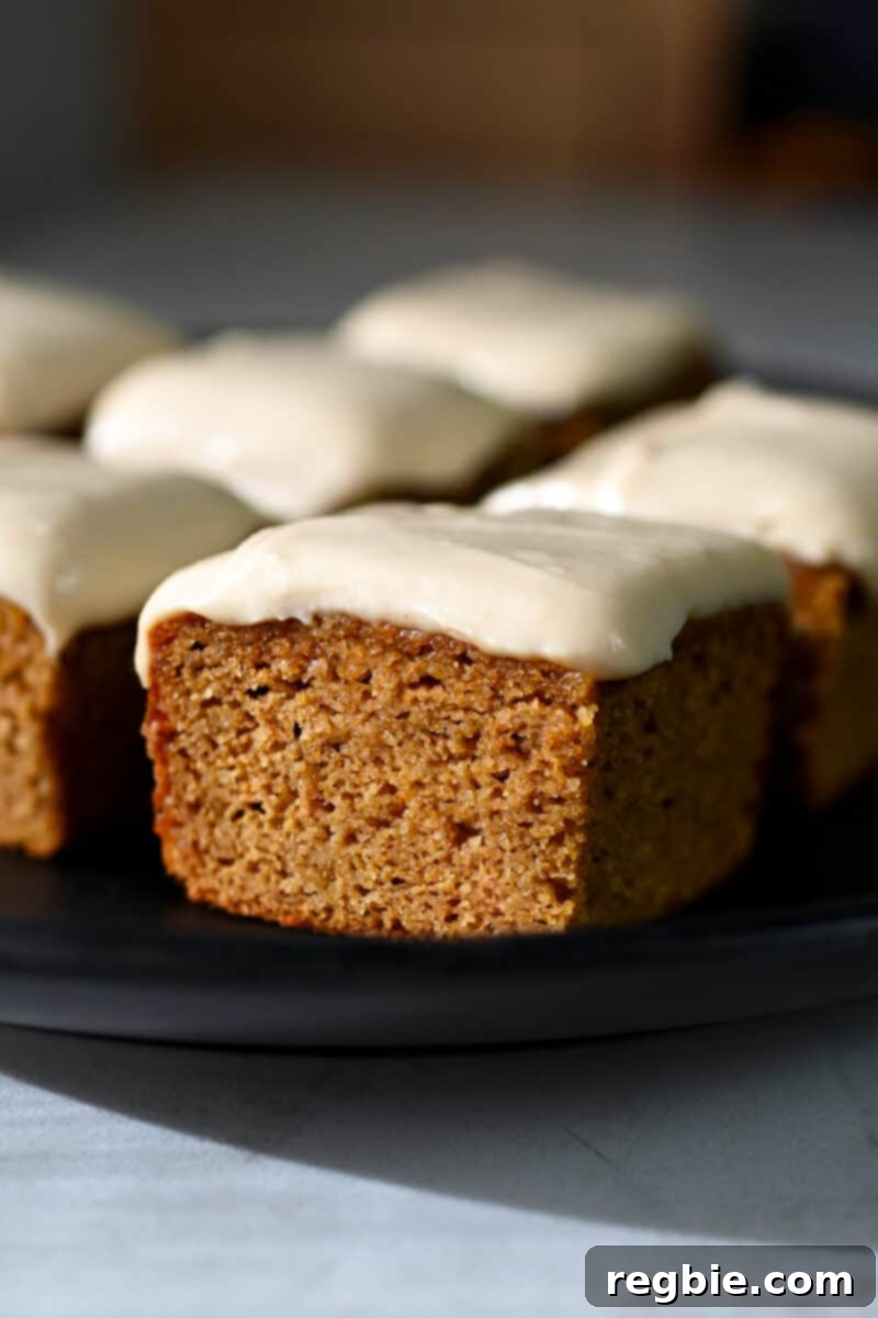 Guilt Free Paleo Pumpkin Bars 2 A side view of a paleo and gluten free pumpkin bar topped with a dairy-free cream cheese frosting, showcasing its moist texture.