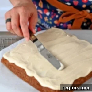 Spreading vegan cream cheese frosting on a square pumpkin cake.