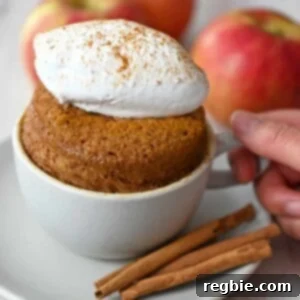 A gluten-free and paleo apple mug cake topped with whipped coconut cream, ready to eat.