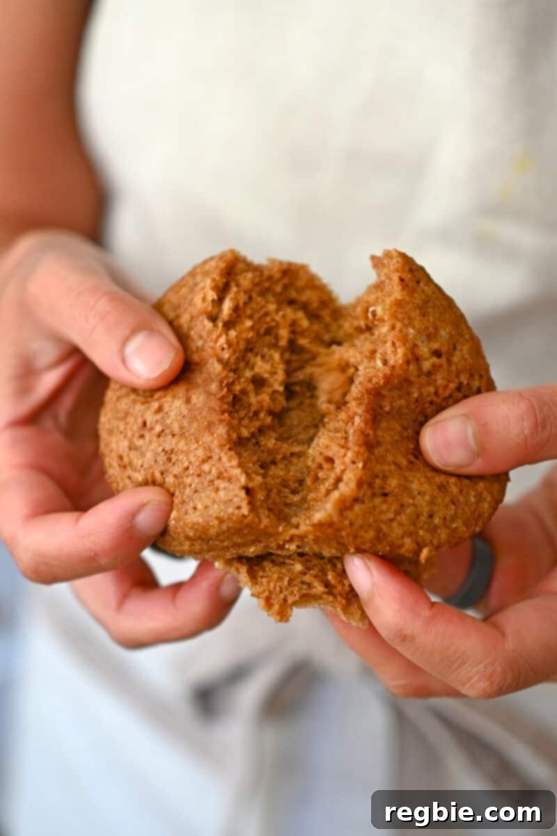 A person gently splitting a fluffy gluten-free apple mug cake in half to reveal its soft, airy texture.