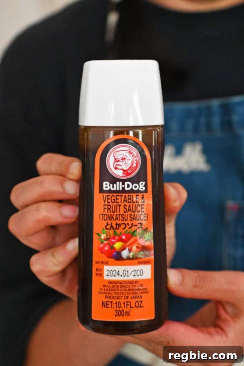 Healthy & Delicious Tonkatsu Sauce (Paleo, Whole30, Vegan) 4 A hand is holding up a bottle of Bulldog Tonkatsu Sauce, the widely recognized commercial version.