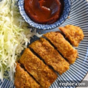 An overhead shot of a blue and white plate with air fryer tonkatsu, shredded cabbage, and homemade Tonkatsu Sauce.