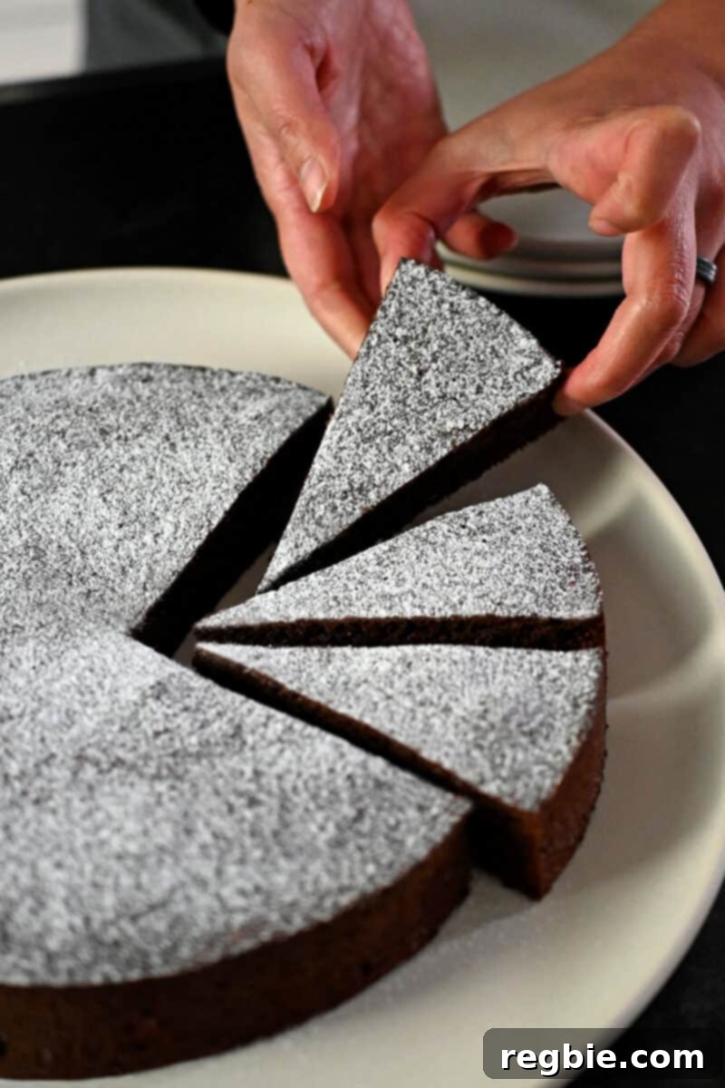 Caprese Chocolate Almond Torte 4 A hand is grabbing a slice of paleo Torta Caprese from a plate.