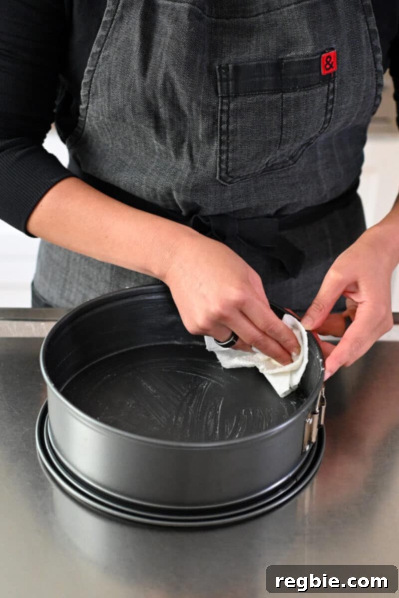 Caprese Chocolate Almond Torte 6 A person in a gray apron is greasing a springform pan with coconut oil.