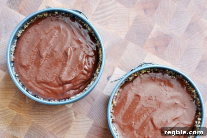Paleo Vegan Gluten Free Chocolate Graham Cracker Pie 14 An overhead shot showcasing two finished paleo chocolate pies, their surfaces smooth and rich, resting on a wooden cutting board before chilling.