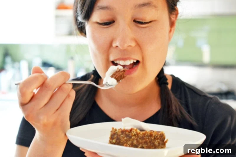 Paleo Vegan Gluten Free Chocolate Graham Cracker Pie 18 A smiling Asian woman enjoying a piece of paleo chocolate pie, her expression conveying pure satisfaction with the delicious dessert.