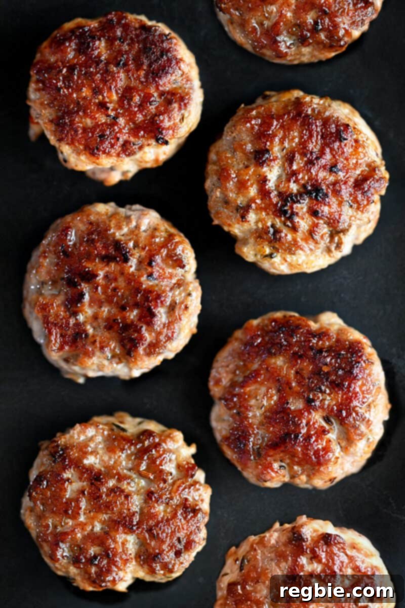 An overhead shot of golden brown homemade Italian sausage patties on a black plate.