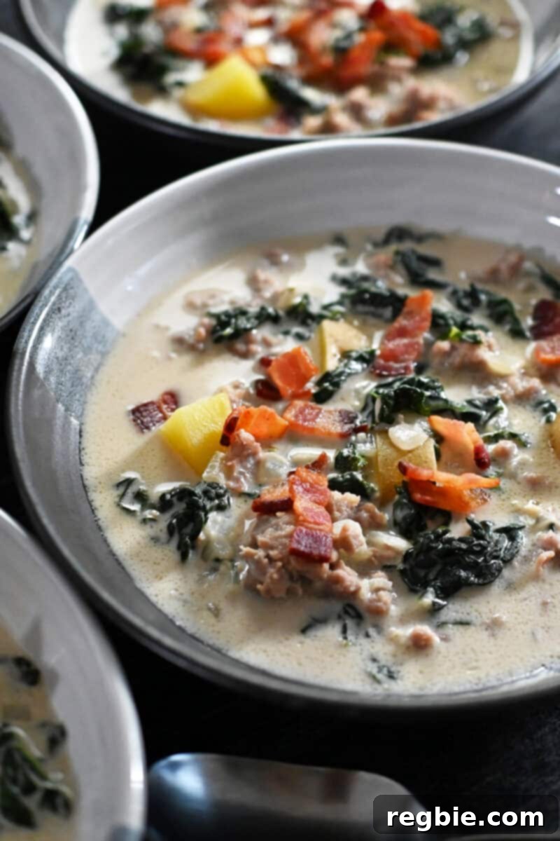 A closeup of a bowl of Whole30 Zuppa Toscana soup topped with crispy bacon bits.