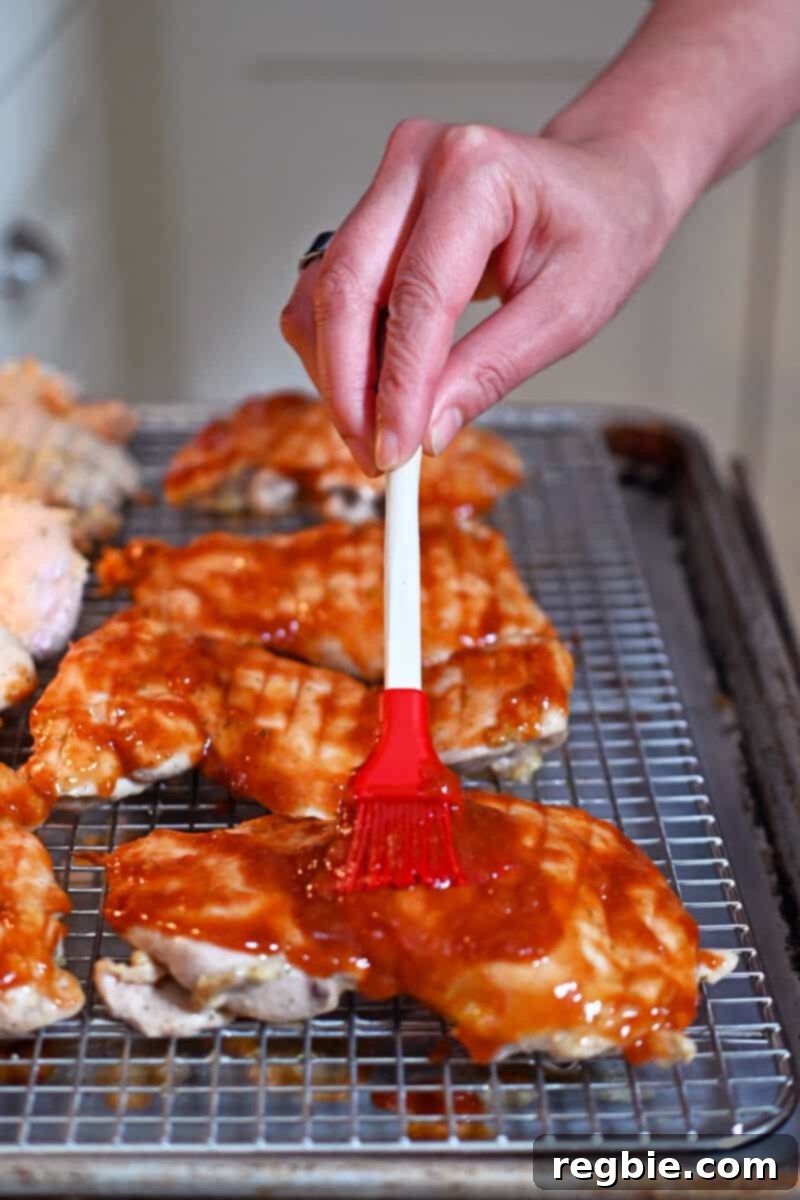 Brushing two-thirds of the delicious Char Siu sauce onto the smooth side of partially cooked boneless, skinless chicken thighs.