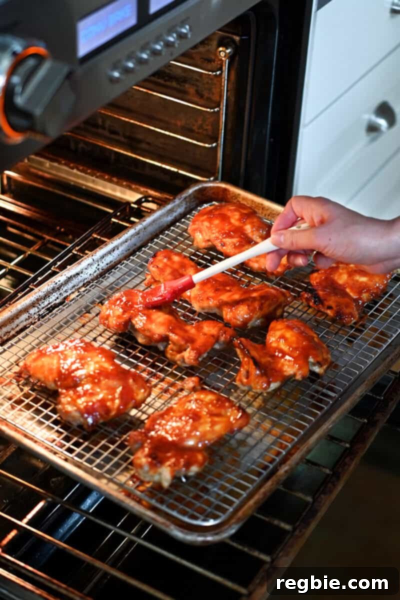 Brushing the remaining Char Siu sauce on the chicken before the final baking time, creating a glossy finish.