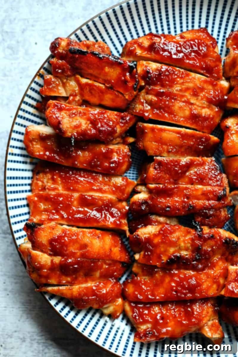 An overhead shot of a blue plate topped with sliced paleo and gluten free char siu chicken, garnished with fresh herbs.