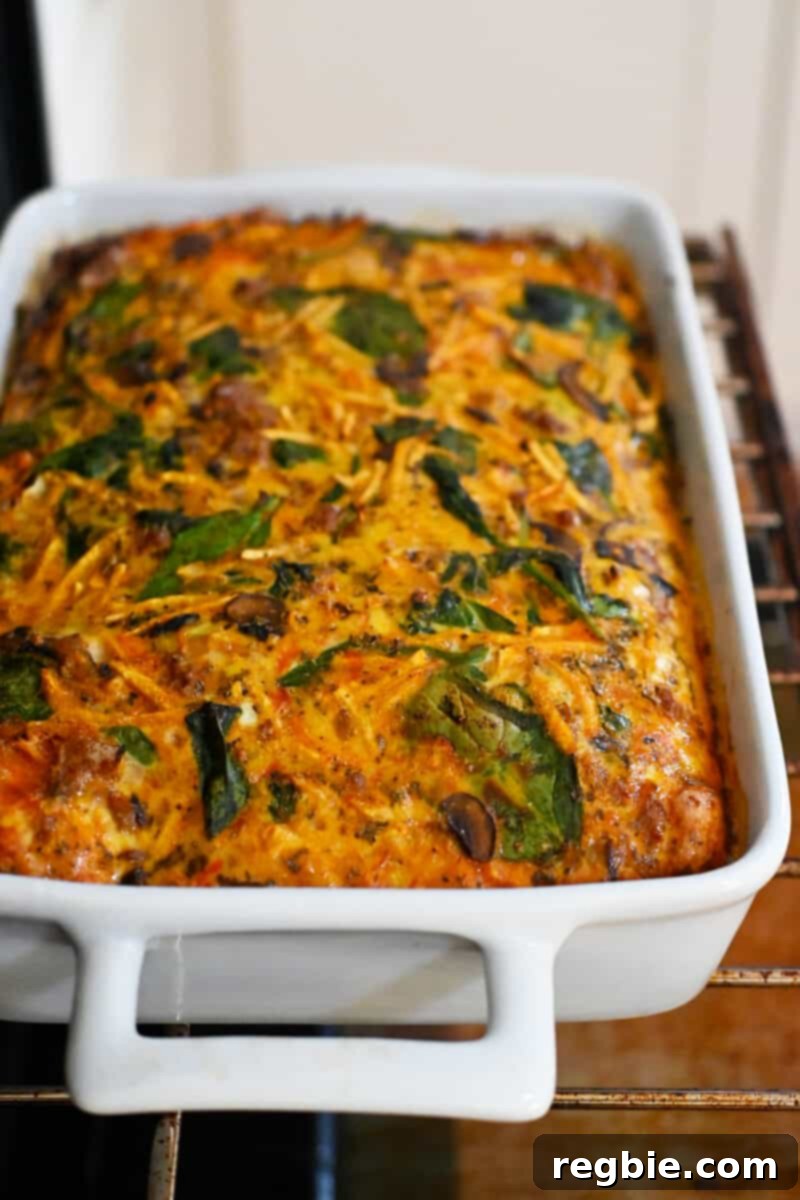A wholesome paleo and gluten-free sausage breakfast casserole baking to perfection on an oven rack inside an open oven, gradually turning golden.