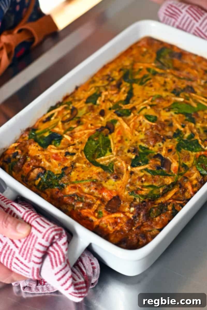 A freshly baked sausage breakfast casserole, just removed from the oven, resting on a stainless steel counter and boasting a beautifully golden-brown top.