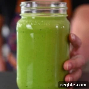 A hand is holding a mason jar filled with paleo, vegan, and Whole30 Green Goddess Dressing.