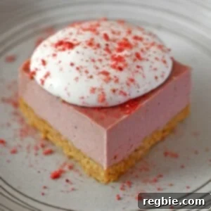 A slice of paleo, vegan, and gluten free strawberry cheesecake bars on a white plate, topped with whipped coconut cream and strawberry powder.