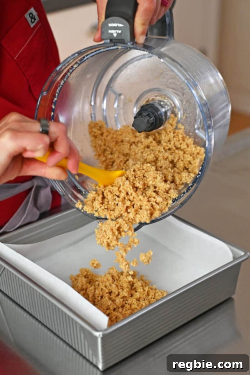 The process of adding the gluten-free crust ingredients into a square baking pan that has been meticulously lined with parchment paper.