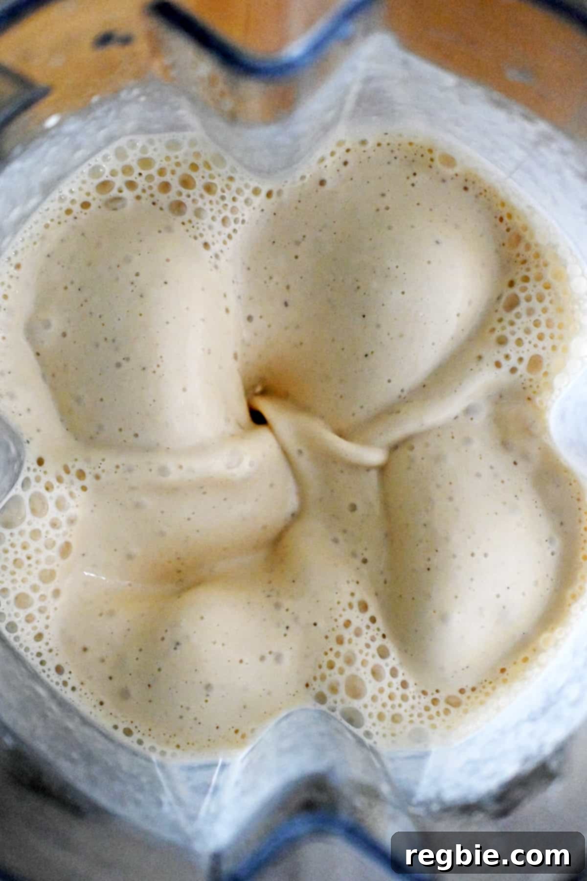 An overhead shot of an open Vitamix blender with a perfectly creamy white sauce inside, ready for the casserole.