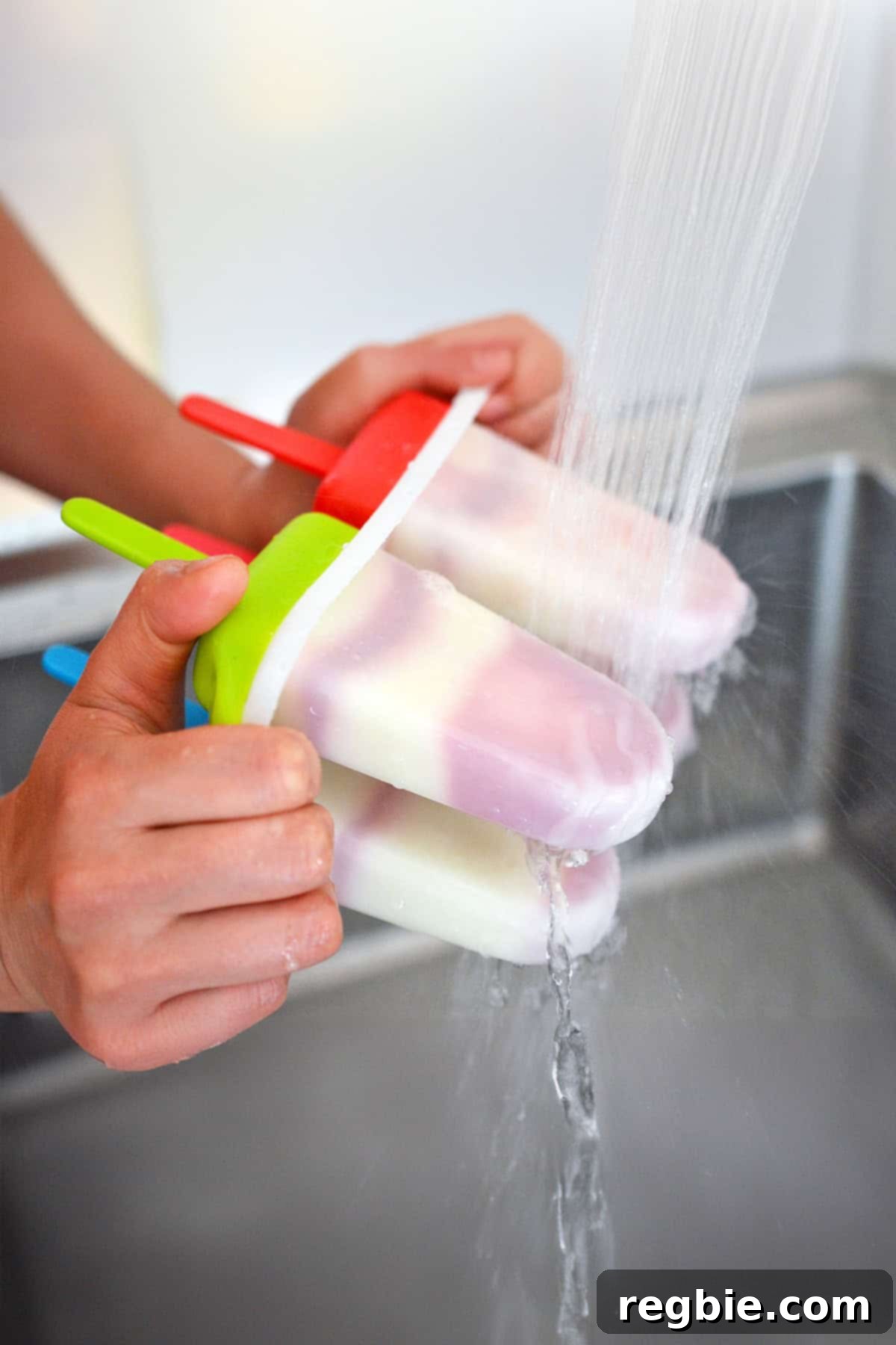 Running a popsicle mold under warm running water to make the frozen popsicles easier to release.