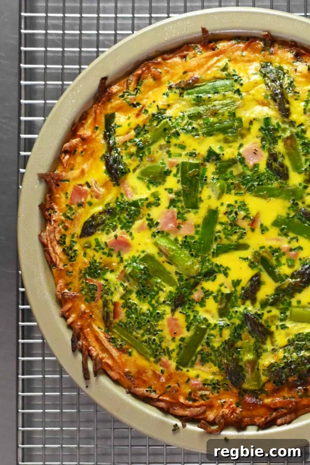 A perfectly baked paleo and Whole30 asparagus quiche, just removed from the oven, resting on a wire rack to cool.